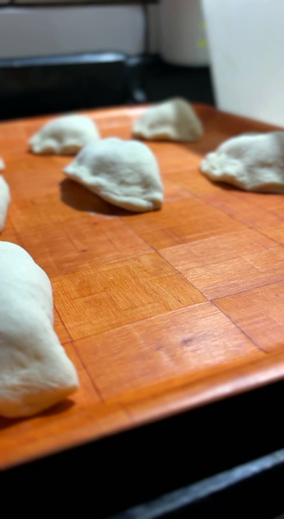 Pierogis crus descansando na tábua de madeira, crescendo antes da fritura