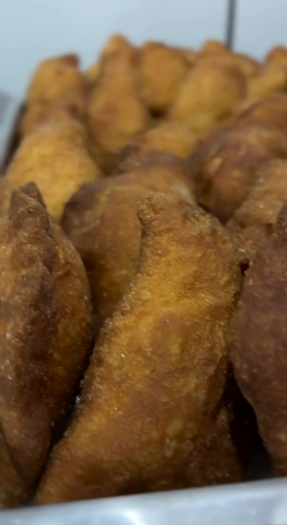 Bandeja cheia de pierogis de feijão dourados na fritura